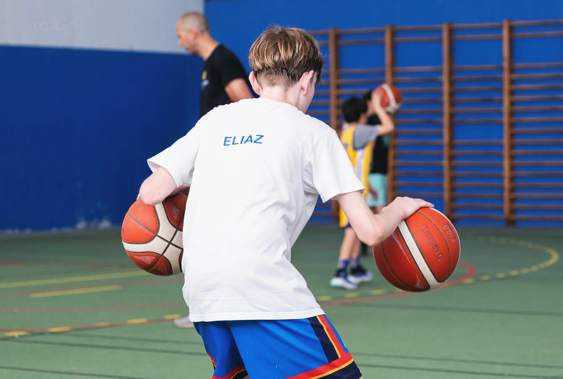 Un jeune joueur dribble avec deux ballons sous le regard de Marc Mercier